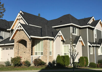 Grey two-storey home with stone details and white-framed windows