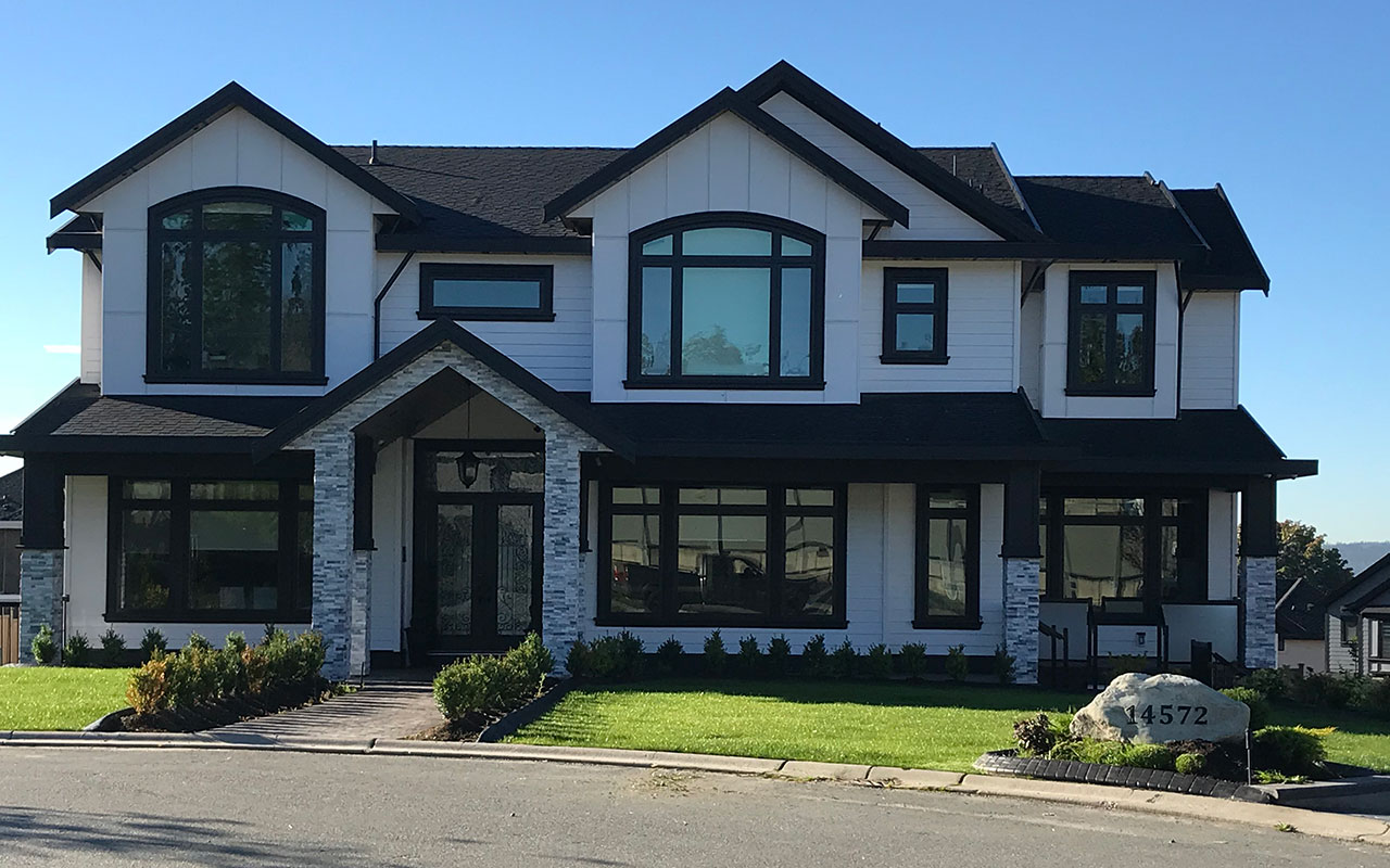 Two-storey home with white-trim windows and a landscaped front lawn
