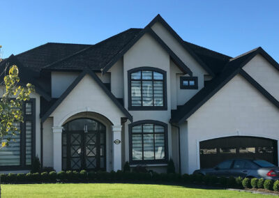 Large white home with arched black windows and a double garage