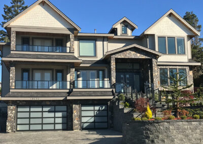 Three-storey home with balconies, stone details and glass garage doors