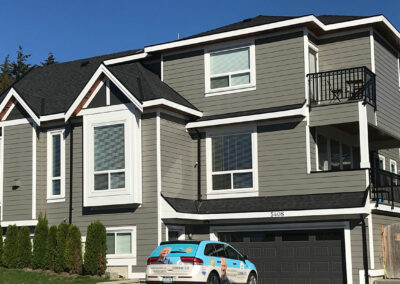 Grey three-storey home with balconies and a garage