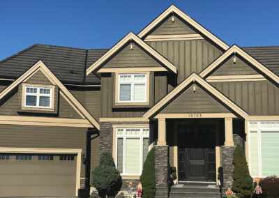 Home with olive siding, stone columns and a double garage