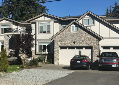 Home with stone and beige cladding, a double garage and two parked vehicles