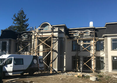 Large home under construction with scaffolding and a work van parked outside