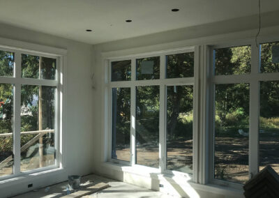 Empty room under construction with large windows and white walls