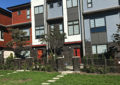 Modern townhomes with red doors and dark stone planters