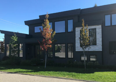 Large dark two-storey home with big windows beside a lawn