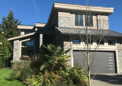 Modern home with a grey garage door, stone cladding and large windows