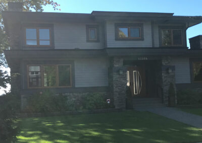 Dark-sided two-storey home with a lawn and tall windows