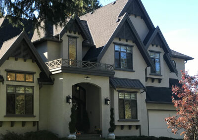 Large cream home with a balcony, dark roof and arched entrance