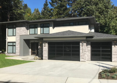 Modern home with a dark double garage door and stone and grey cladding