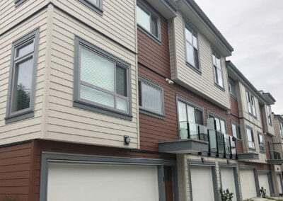 Townhome with beige and red panels, a garage and large windows
