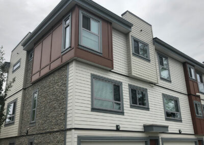 Corner townhome with stone, wood-look and grey cladding