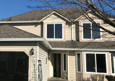 Beige two-storey home with white-framed windows and a bay window