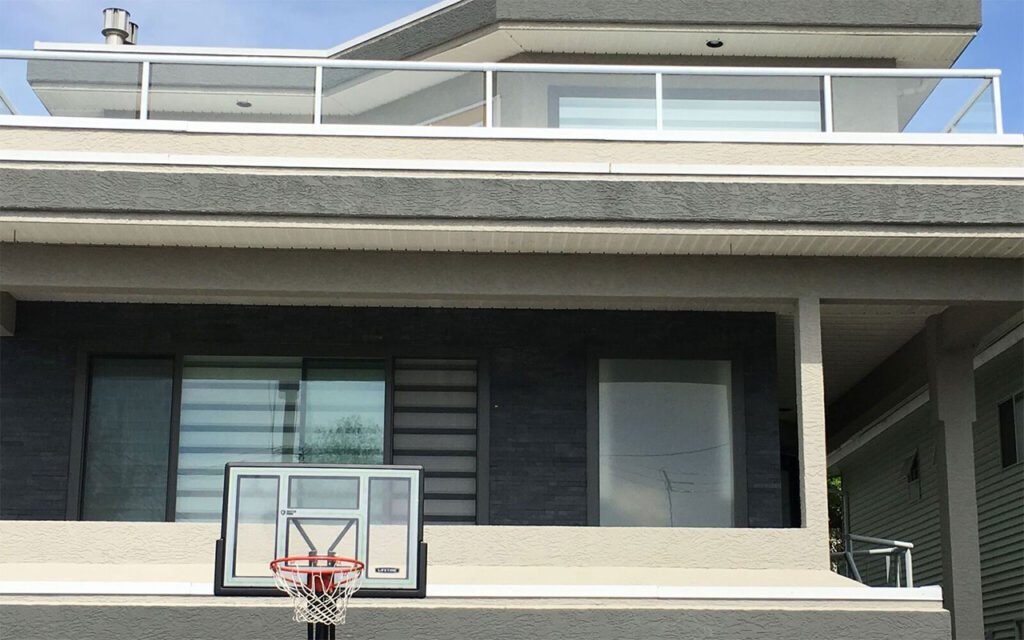 Balcony with a basketball hoop above a garage and large windows with blinds