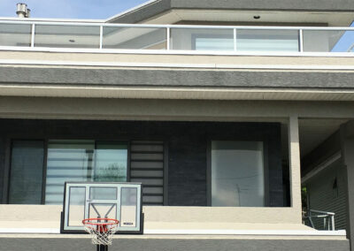 Balcony with a basketball hoop above a garage and large windows with blinds