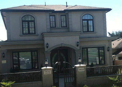 Grey two-storey home with arched windows and a gated entrance