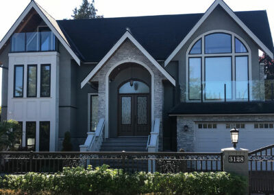 Large home with arched upper windows, stone trim and a double front door