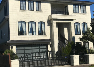 Cream home with tall arched windows, columns and a gated garage