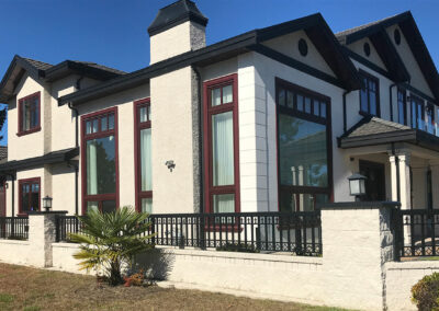 Cream and dark home with red-framed windows and a black railing