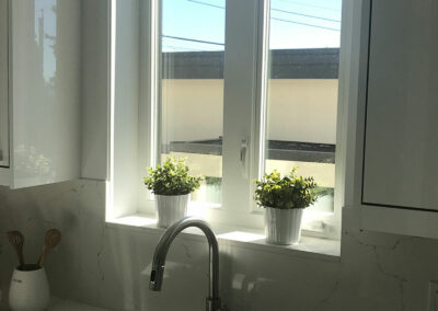 Kitchen window with a white frame, plant pots and a tap