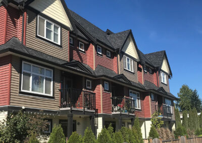 Row of red and brown townhomes with white-framed windows