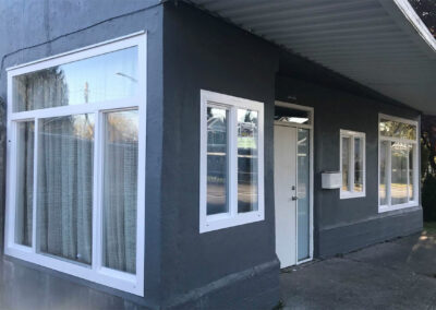 Large white-framed windows beside a door on a dark grey wall