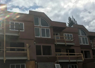 Brown apartment building with balconies and large arched windows under a cloudy sky